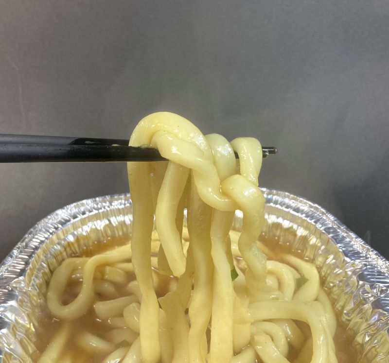 池田食品工業(株) 鍋焼カレーうどん ねぎ入りのうどんを箸でつまむ