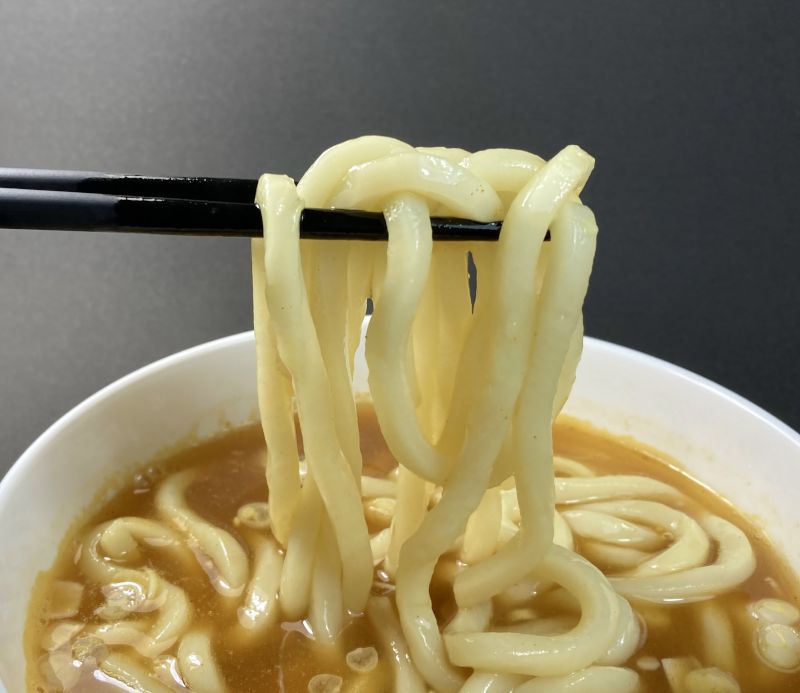 お蕎麦屋さんのカレーうどんをはしでつまむ