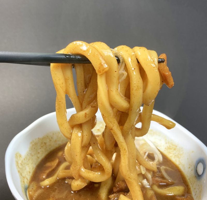 株式会社キャメル珈琲 もへじ お出汁の効いたカレーうどんを箸でつまむ