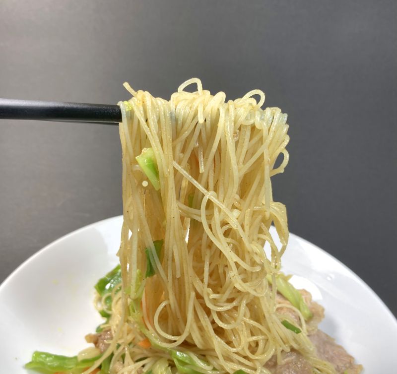ケンミン食品株式会社 カレー焼ビーフンを箸でつまむ