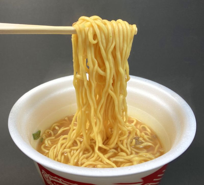 スーパーカップ1.5倍 トマトカレー味ラーメンカップの麺を箸でつまむ