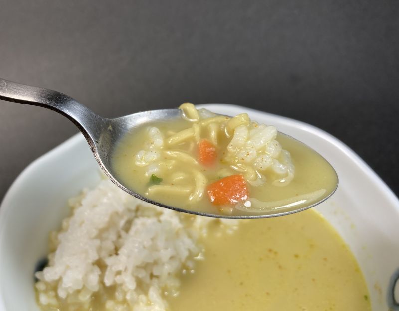 グリーンカレーラーメンをスプーンですくう