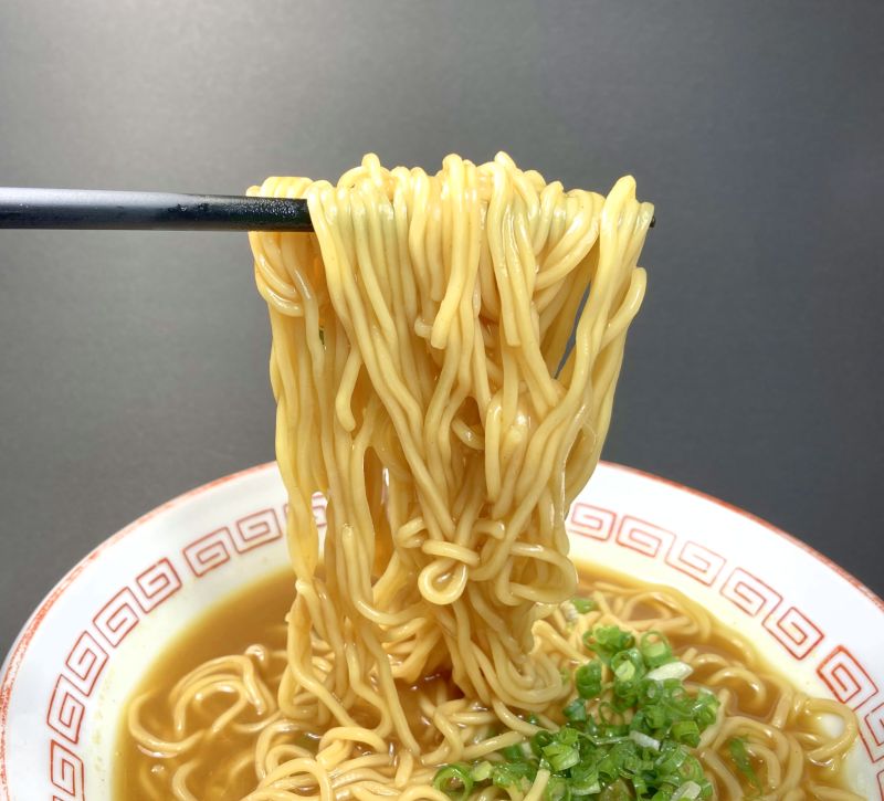 株式会社菊水 味の大王 元祖カレーラーメン 中辛の麺をはしでつまみ上げる