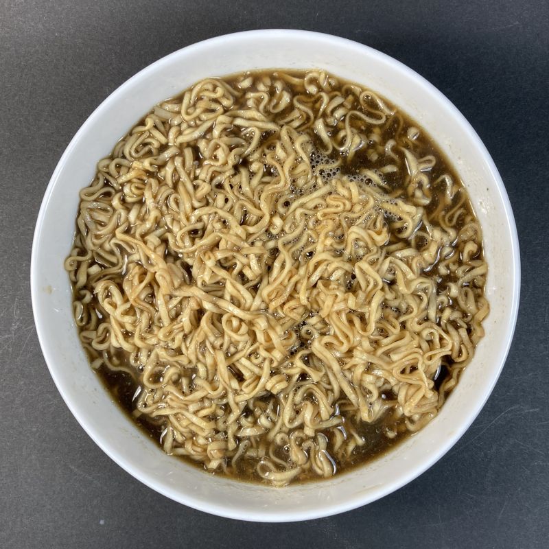 日清食品株式会社 チキンラーメンブラック スパイスカレー味の麺を混ぜる