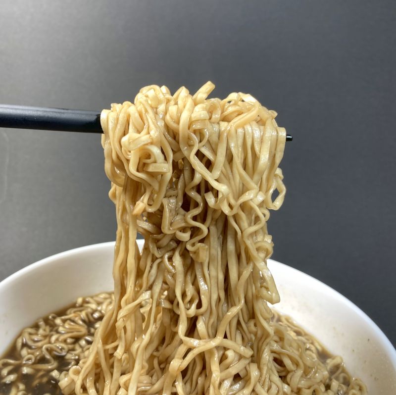 日清食品株式会社 チキンラーメンブラック スパイスカレー味の麺をつまむ