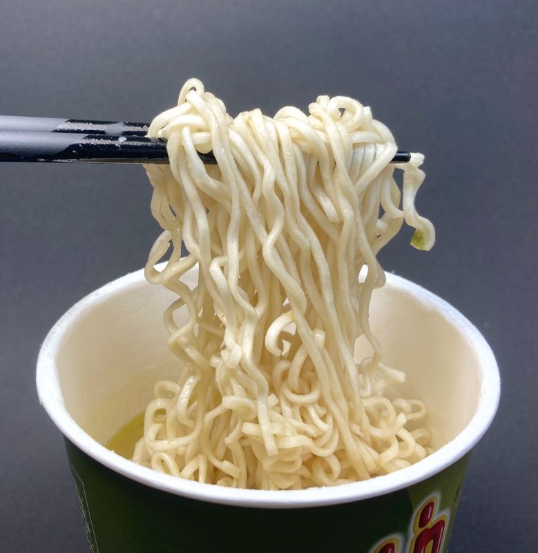 株式会社オーバーシーズ タイプレジデント グリーンカレーの麺を箸でつまむ