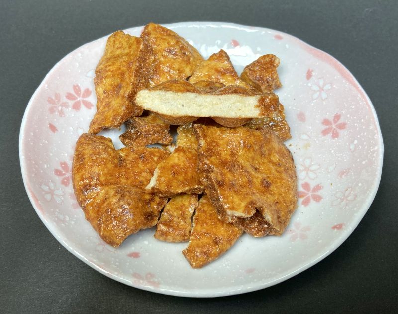 亀田製菓株式会社 技のこだ割り 和風だしカレー味のおせんべいを半分にカット