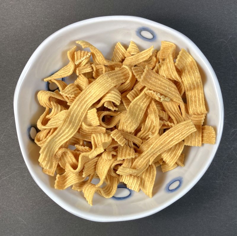 株式会社おやつカンパニー 期間限定 ブタメン 太麺スナック カレーラーメン味をお皿に盛る