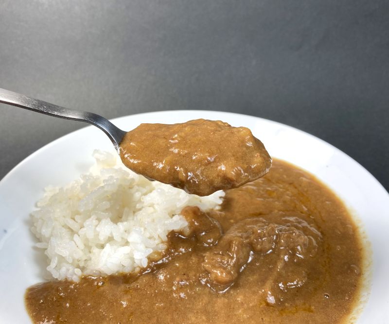 国分北海道株式会社 函館 トマトクリームチーズカレーをスプーンですくう画像