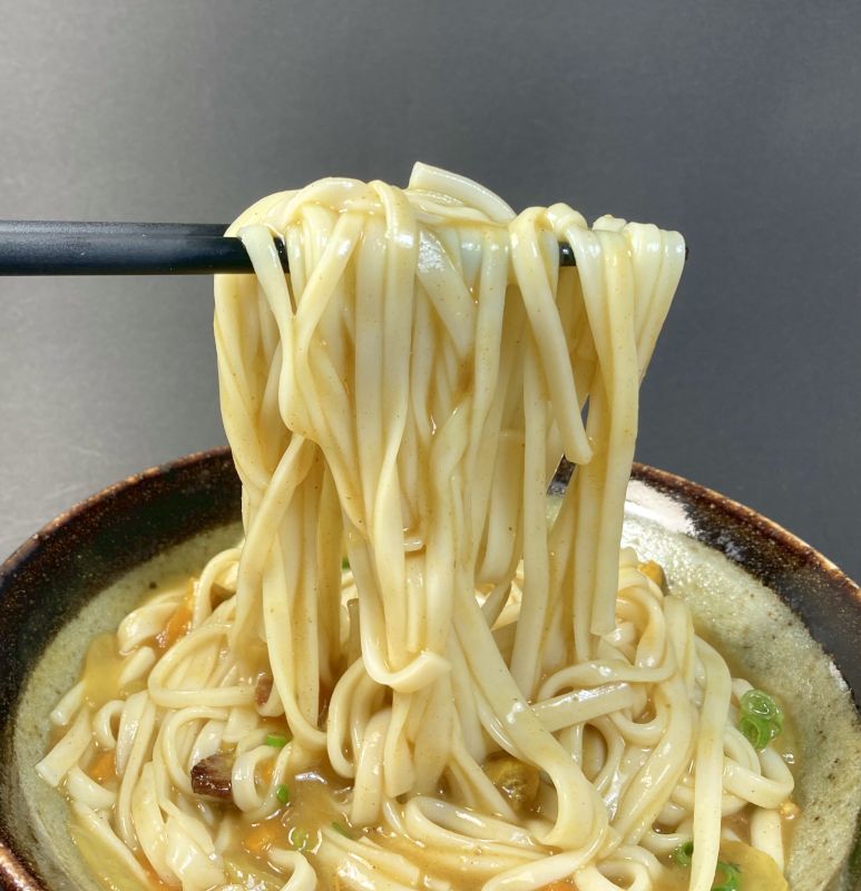 大塚食品株式会社 和のボンカレー 中辛のうどんを箸でつまむ